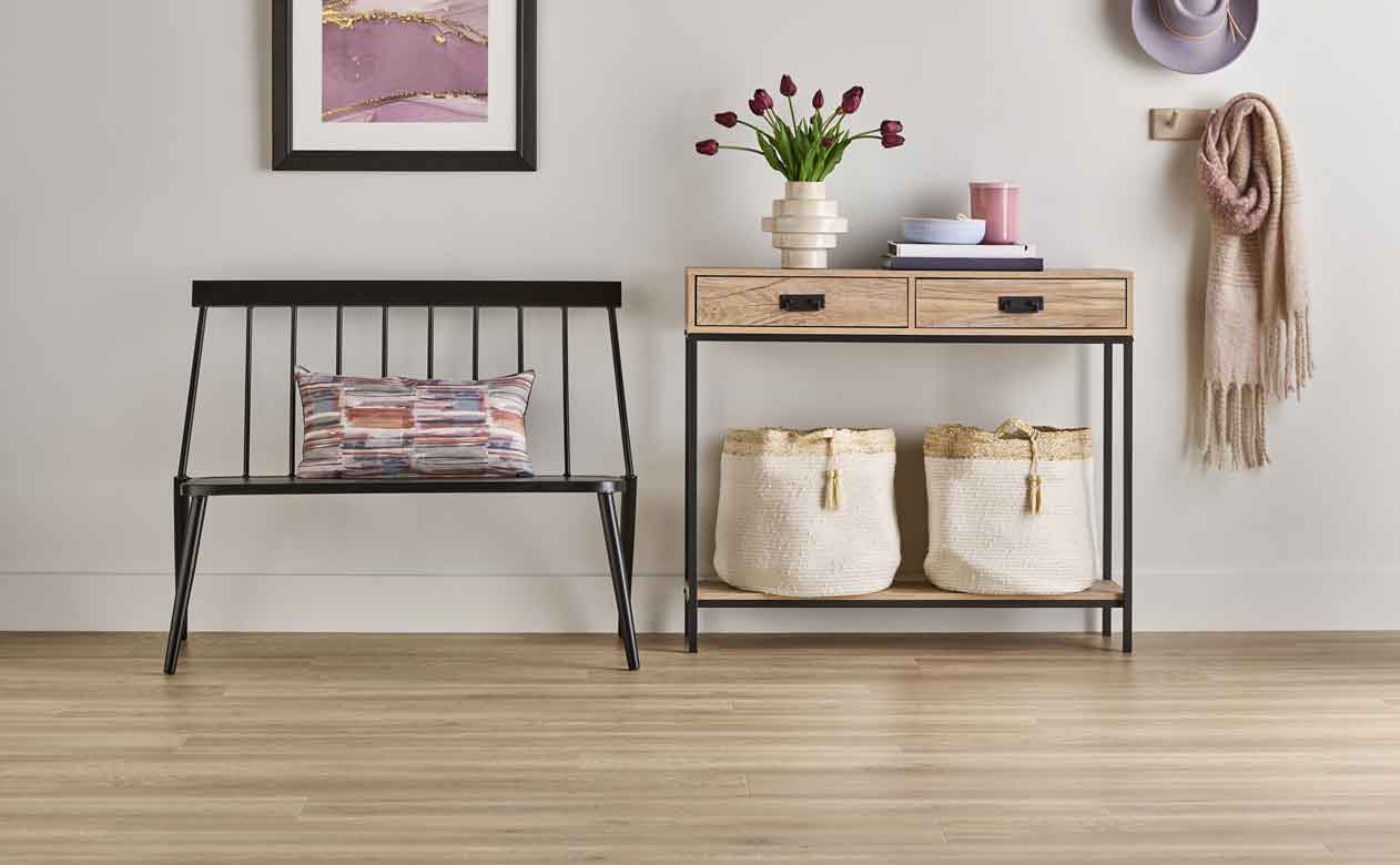 light wood laminate floors in entryway with black bench 